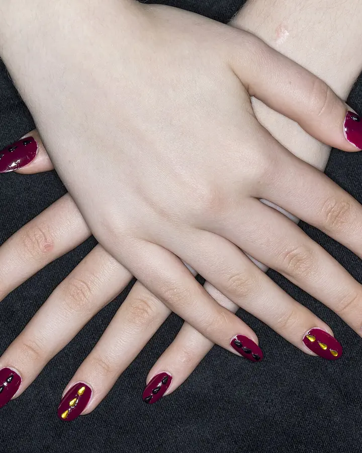 Burgundy almond nails on dark fabric