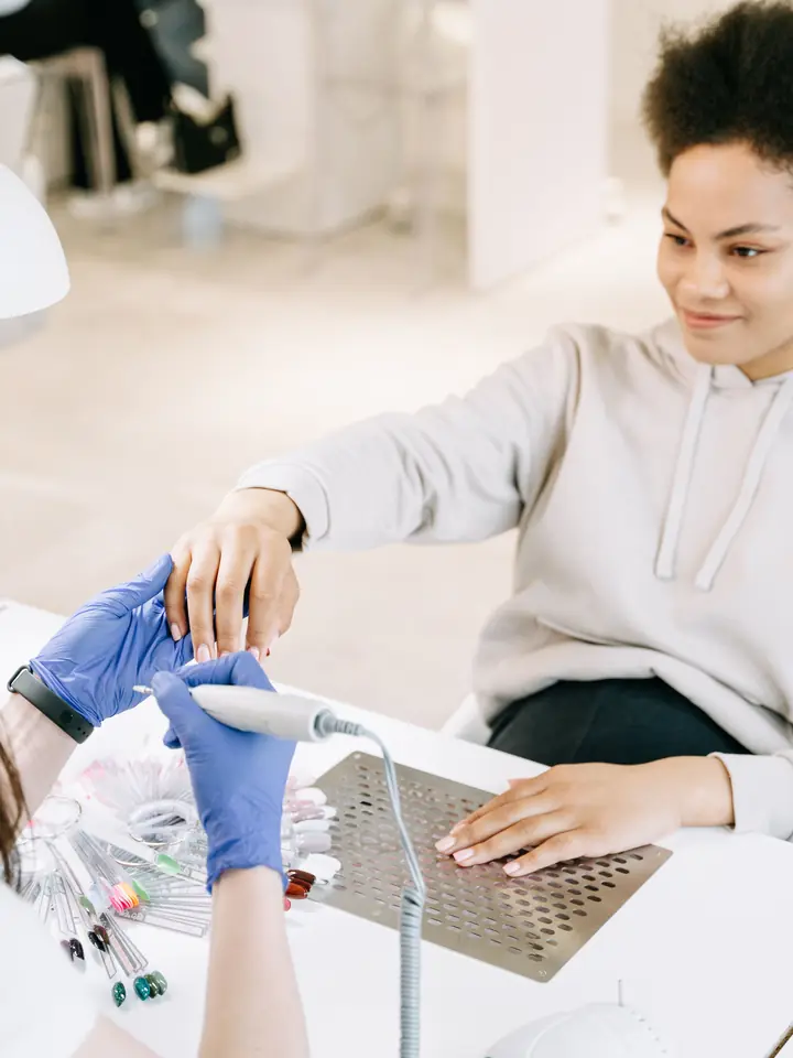 Client having her nails maintained at a bright salon table